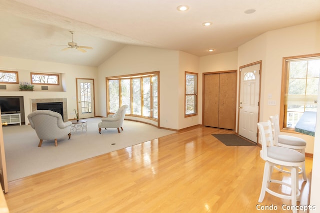 entrance foyer with wood finished floors, baseboards, recessed lighting, a tile fireplace, and vaulted ceiling