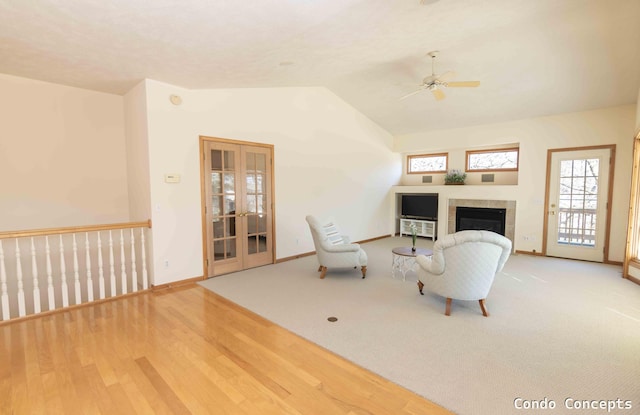 living room with french doors, wood finished floors, a tiled fireplace, and vaulted ceiling