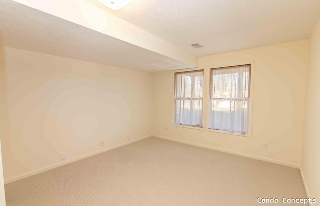 carpeted spare room featuring visible vents, a textured ceiling, and baseboards