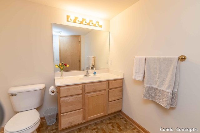 bathroom with baseboards, toilet, and vanity