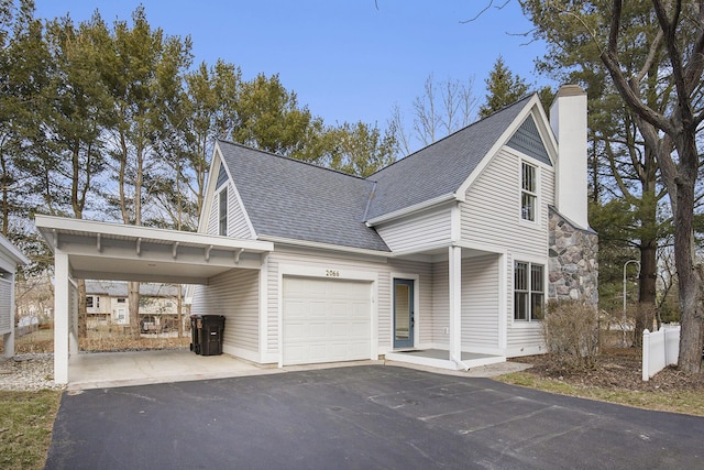 view of front facade with an attached carport, roof with shingles, a chimney, a garage, and aphalt driveway