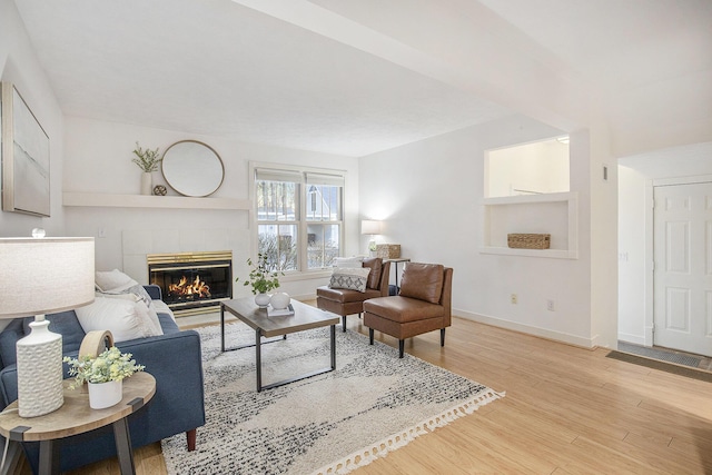 living room with wood finished floors, baseboards, and a tile fireplace