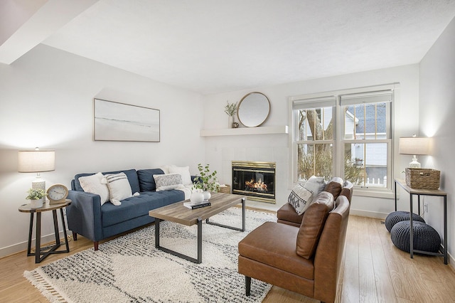 living area featuring a fireplace, baseboards, and wood finished floors