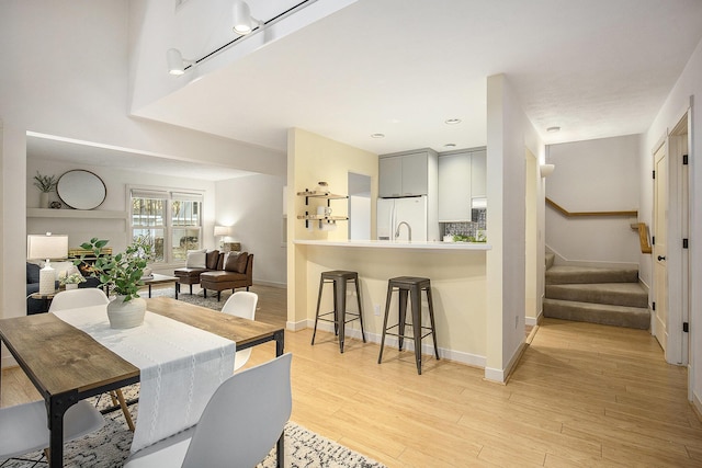 dining room featuring stairway, baseboards, and light wood-type flooring