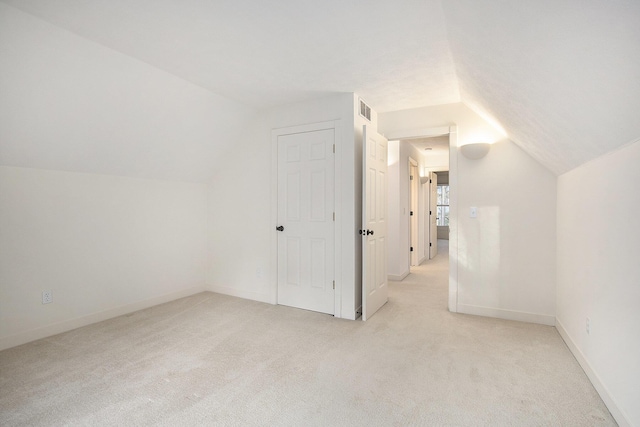 additional living space featuring visible vents, lofted ceiling, light colored carpet, and baseboards