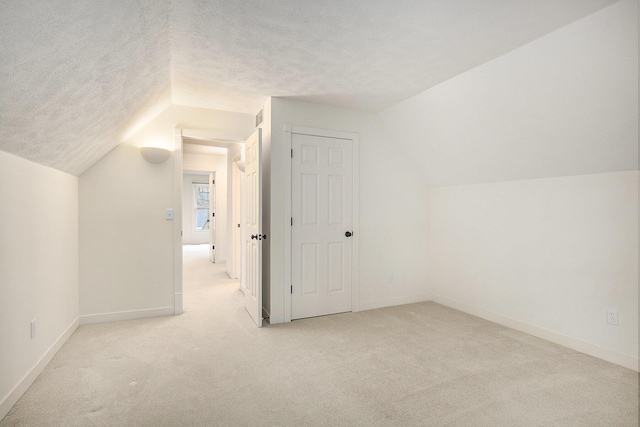 additional living space featuring baseboards, lofted ceiling, a textured ceiling, and carpet