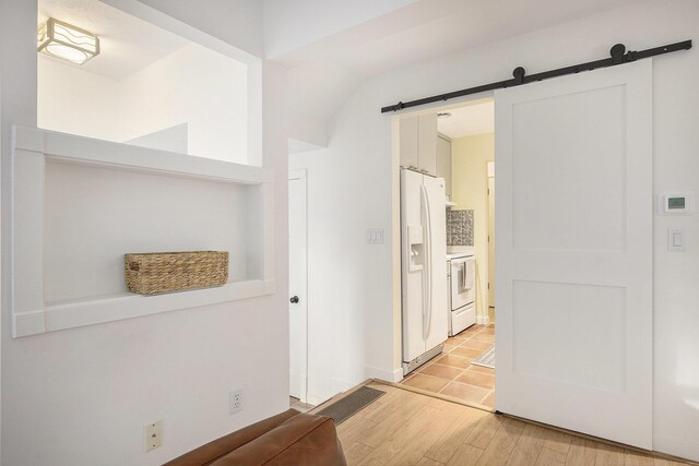 corridor featuring light wood-style floors and a barn door