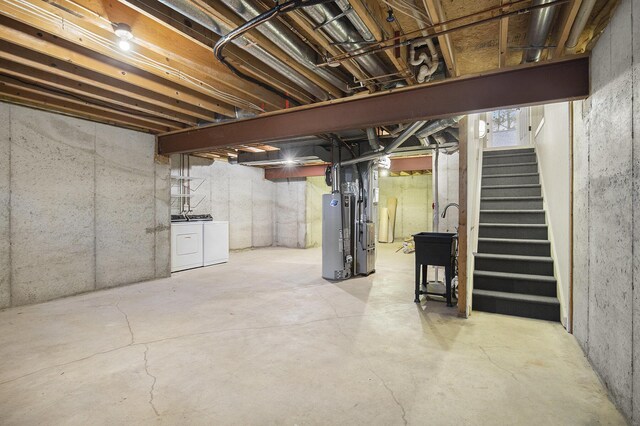 unfinished below grade area featuring washing machine and dryer, gas water heater, stairs, and a sink