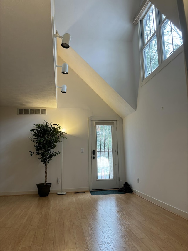 entrance foyer featuring a towering ceiling, baseboards, visible vents, and light wood finished floors