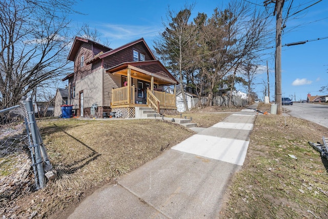 view of front of home featuring a front lawn, fence, a shed, covered porch, and an outdoor structure