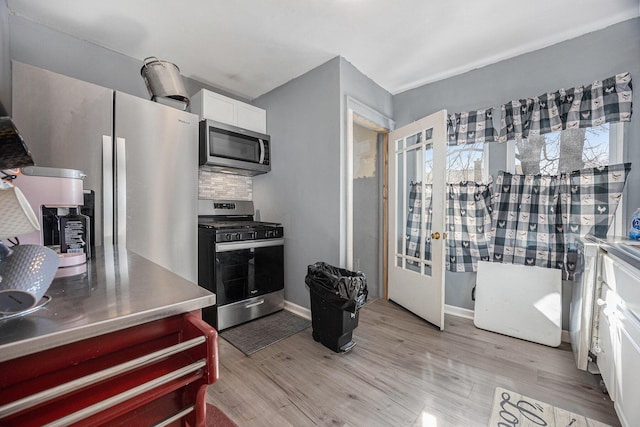 kitchen with backsplash, stainless steel countertops, appliances with stainless steel finishes, light wood-style floors, and white cabinetry