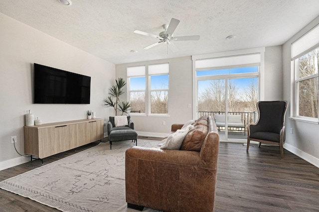 living room with a textured ceiling, a ceiling fan, baseboards, and dark wood-style flooring