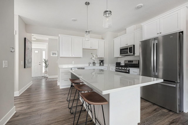 kitchen with a kitchen breakfast bar, dark wood-style floors, a center island, white cabinetry, and stainless steel appliances