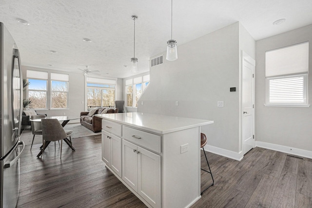 kitchen with a kitchen bar, plenty of natural light, dark wood-style floors, and freestanding refrigerator