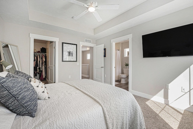 bedroom featuring baseboards, a tray ceiling, a spacious closet, a closet, and carpet flooring