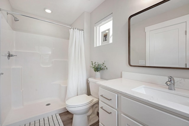 bathroom with vanity, a shower stall, toilet, and wood finished floors