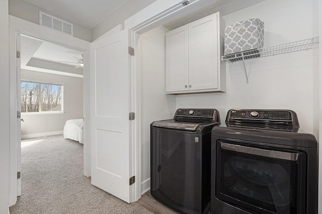 laundry room with visible vents, ceiling fan, light colored carpet, washer and dryer, and cabinet space