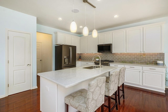 kitchen featuring dark wood-style floors, decorative backsplash, appliances with stainless steel finishes, and a sink