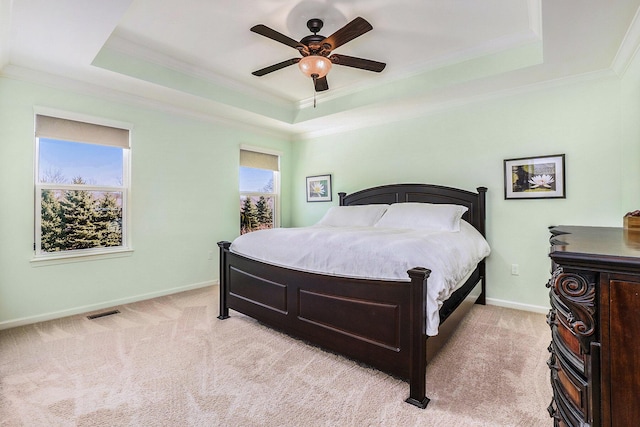 bedroom featuring a tray ceiling, crown molding, light colored carpet, and visible vents