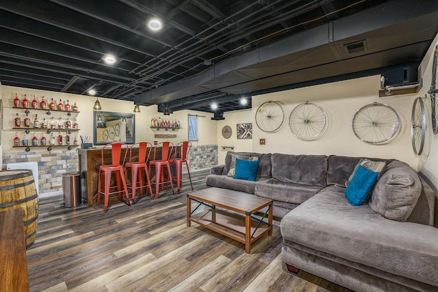 living room with visible vents, a bar, and wood finished floors