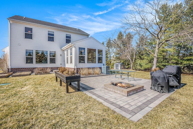 back of property with a patio area, a fire pit, and a lawn