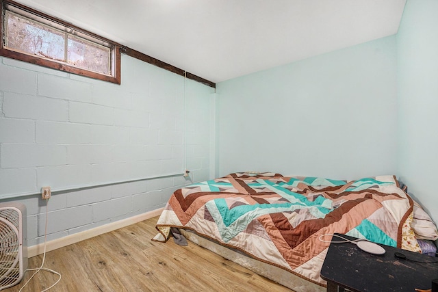 bedroom featuring wood finished floors and concrete block wall