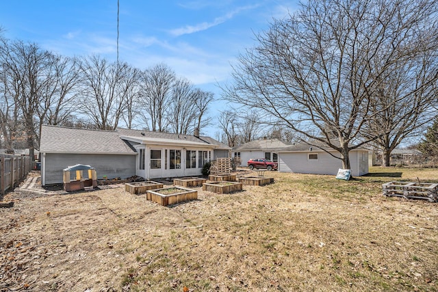 rear view of house featuring a vegetable garden, a yard, and fence