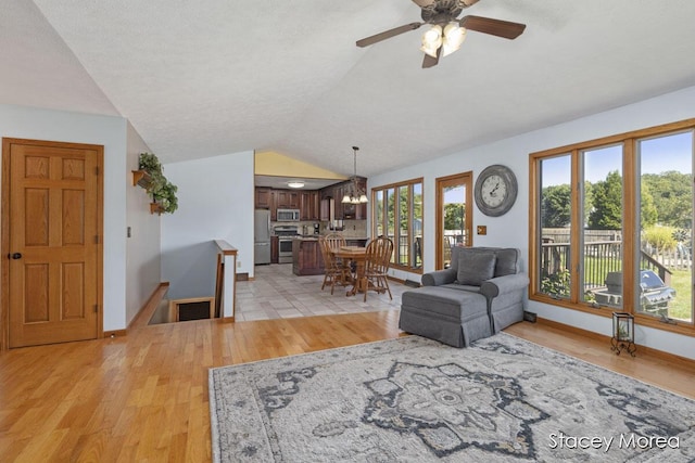 living area with vaulted ceiling, baseboards, and light wood-type flooring