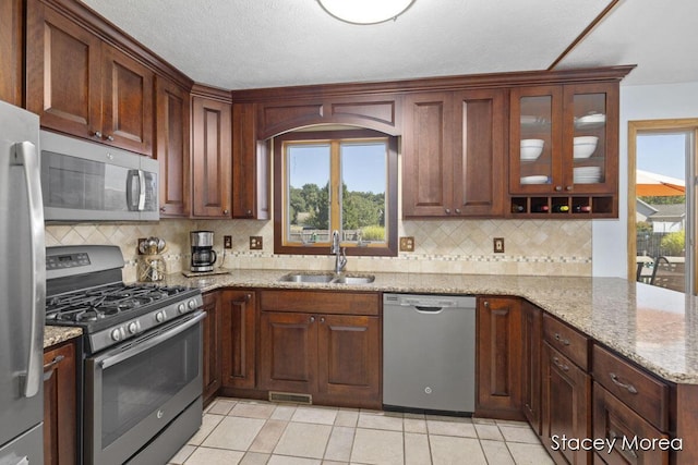 kitchen featuring light stone counters, visible vents, a sink, appliances with stainless steel finishes, and backsplash