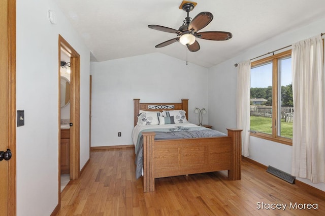 bedroom featuring light wood finished floors, visible vents, baseboards, and vaulted ceiling