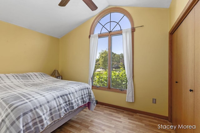 bedroom featuring a closet, lofted ceiling, baseboards, and light wood-style flooring