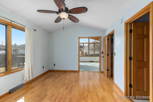 empty room featuring light wood finished floors, visible vents, plenty of natural light, and lofted ceiling