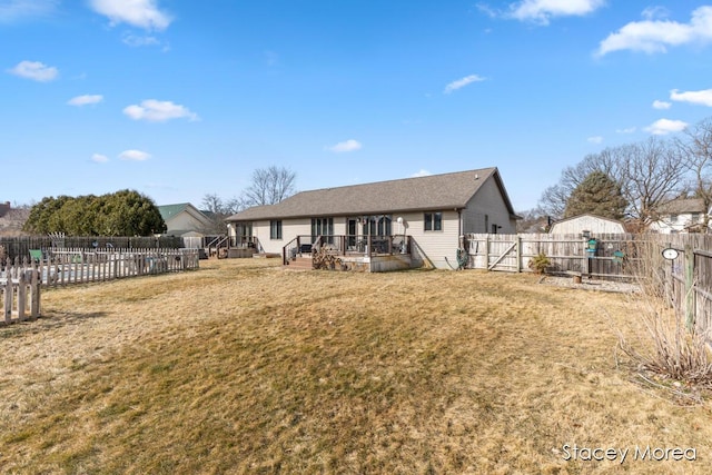 back of property with a deck, a lawn, and a fenced backyard