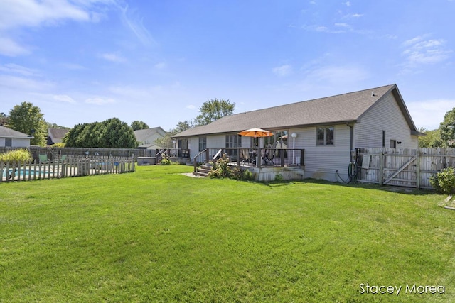 rear view of house with a wooden deck, a yard, and fence