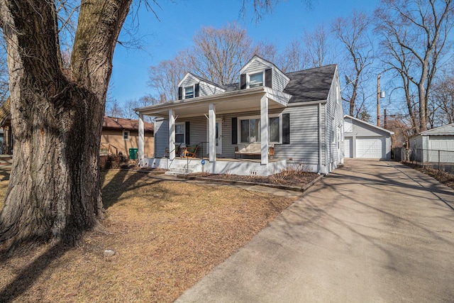 cape cod home featuring an outdoor structure, covered porch, and a detached garage