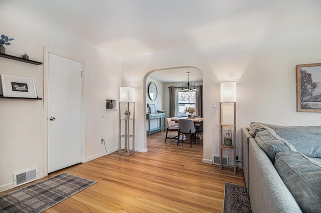 interior space featuring arched walkways, visible vents, light wood-style flooring, and baseboards