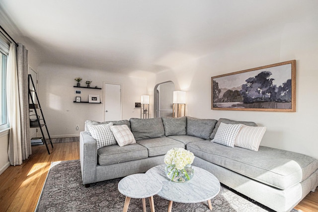 living area featuring arched walkways, baseboards, and wood finished floors