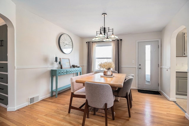 dining room with visible vents, arched walkways, light wood finished floors, and baseboards