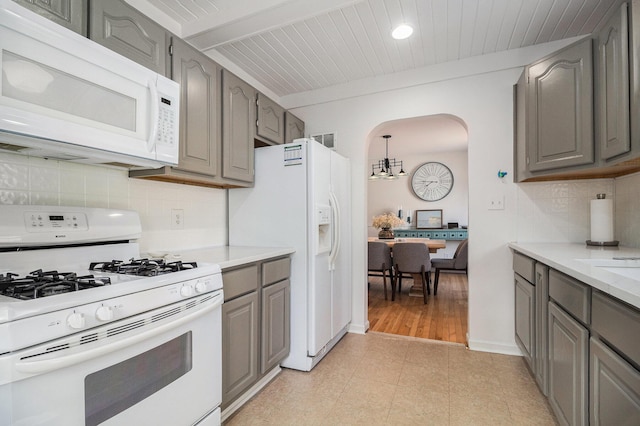 kitchen with white appliances, arched walkways, gray cabinetry, and light countertops