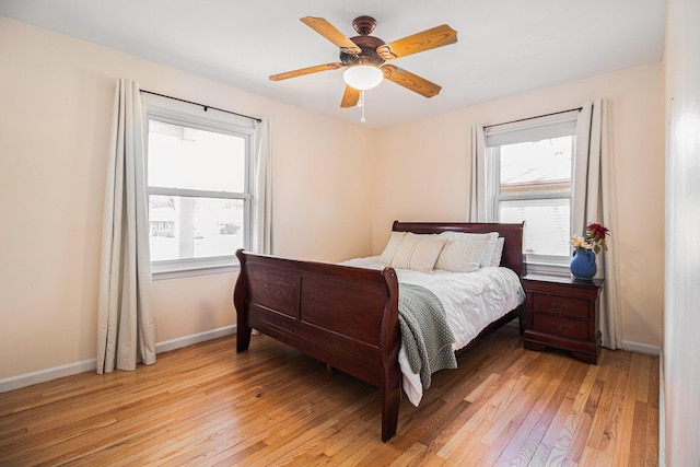 bedroom featuring multiple windows, baseboards, light wood-type flooring, and ceiling fan