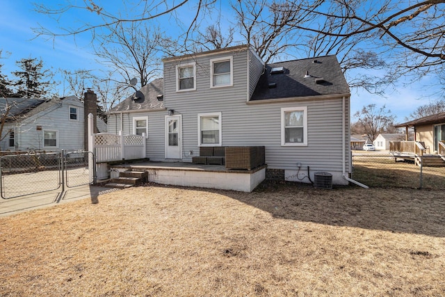 rear view of property featuring a patio area, fence, roof with shingles, and a gate