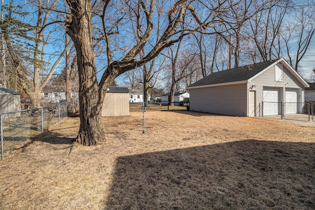 view of yard with a detached garage, an outdoor structure, and fence