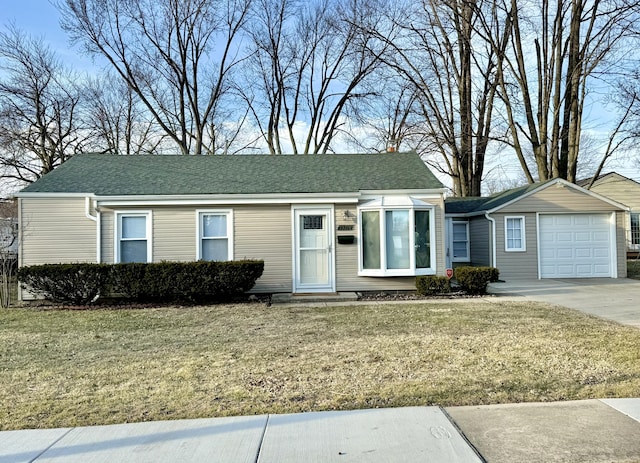 view of front of property with a front yard, concrete driveway, a garage, and a shingled roof