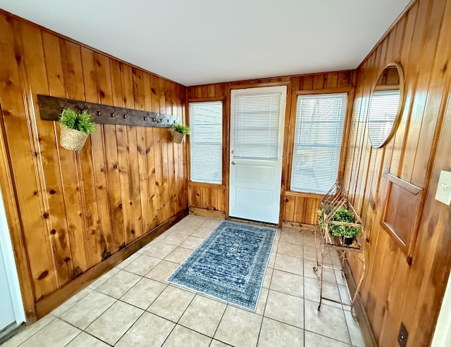 doorway to outside featuring light tile patterned floors and wood walls