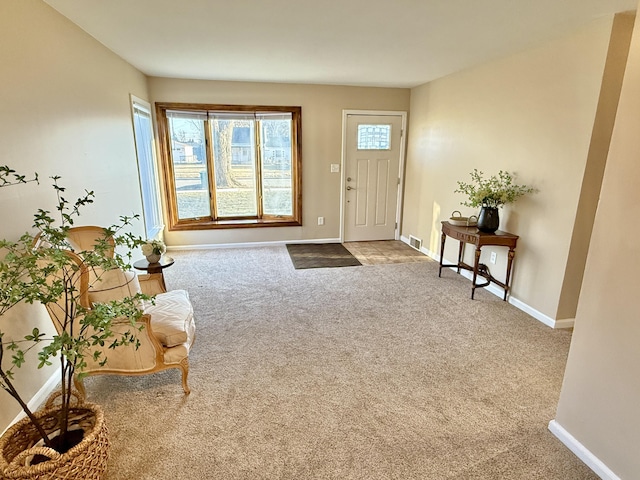 foyer featuring baseboards, carpet floors, and visible vents