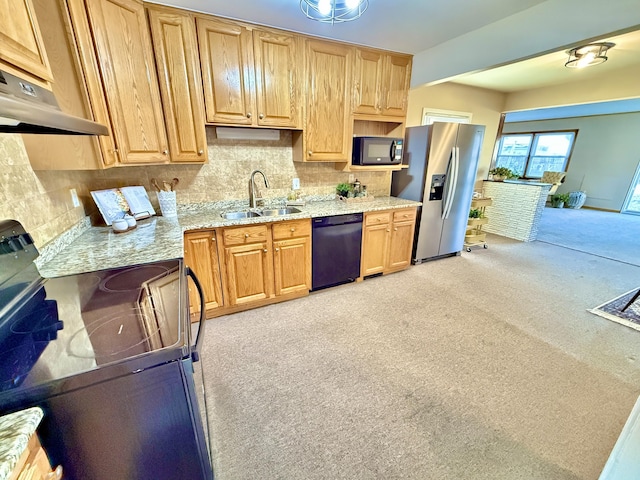 kitchen featuring light stone countertops, a sink, black appliances, under cabinet range hood, and tasteful backsplash