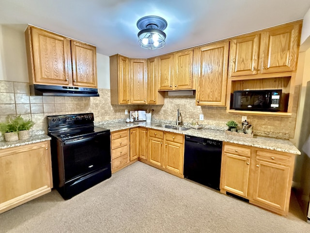 kitchen featuring light stone countertops, a sink, black appliances, under cabinet range hood, and backsplash