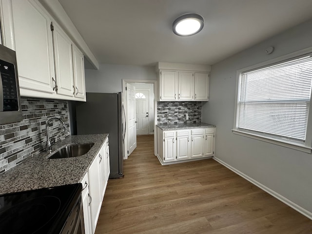 kitchen featuring white cabinetry, baseboards, light wood finished floors, and a sink