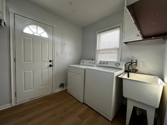 clothes washing area featuring wood finished floors, electric panel, cabinet space, a sink, and independent washer and dryer