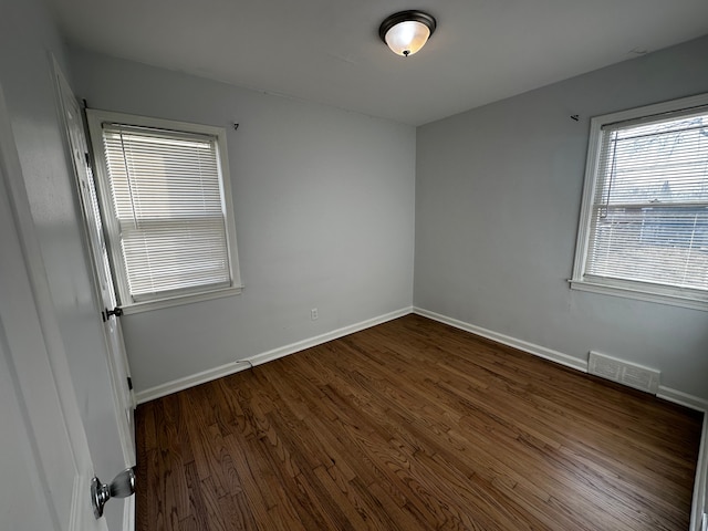 unfurnished room featuring dark wood-type flooring, baseboards, and visible vents